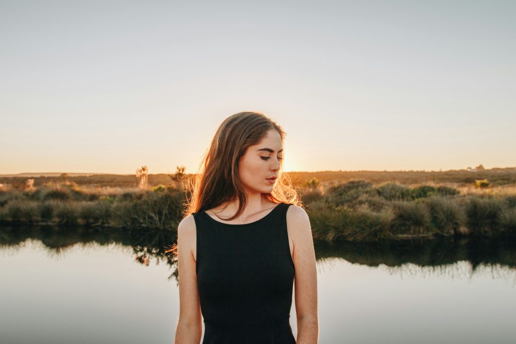 image of a women standing next to a lake at sunset